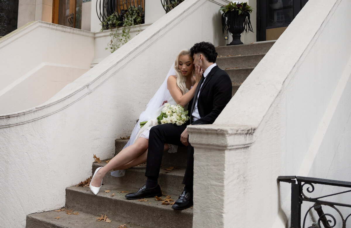 Couple sharing a quiet moment on a NYC step surrounded by city life.