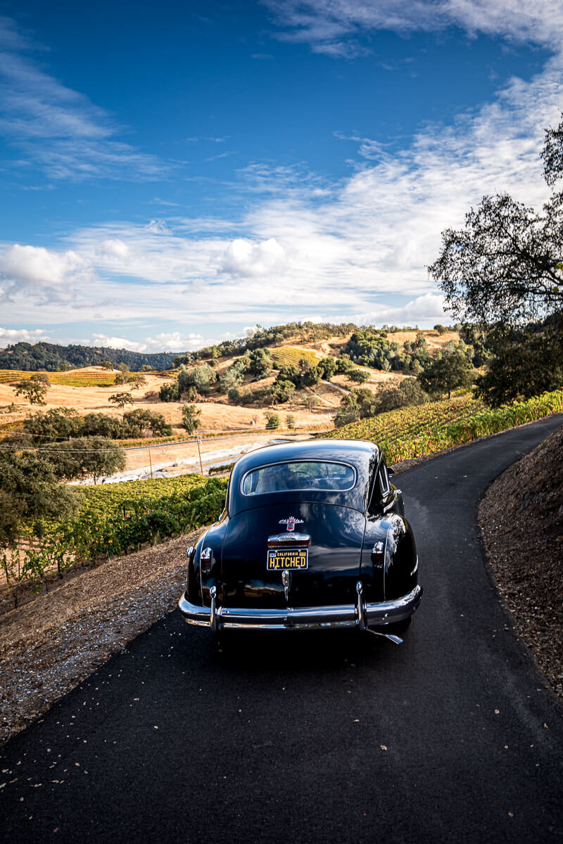 The bride and groom make a stylish getaway in a classic car, the perfect ending to their vineyard ceremony at Airola Road Vineyards.