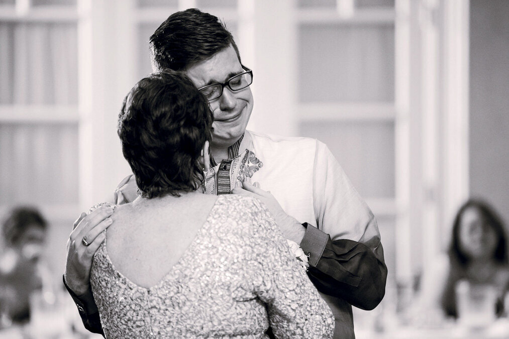 A black and white photo of a groom dancing with his mother.