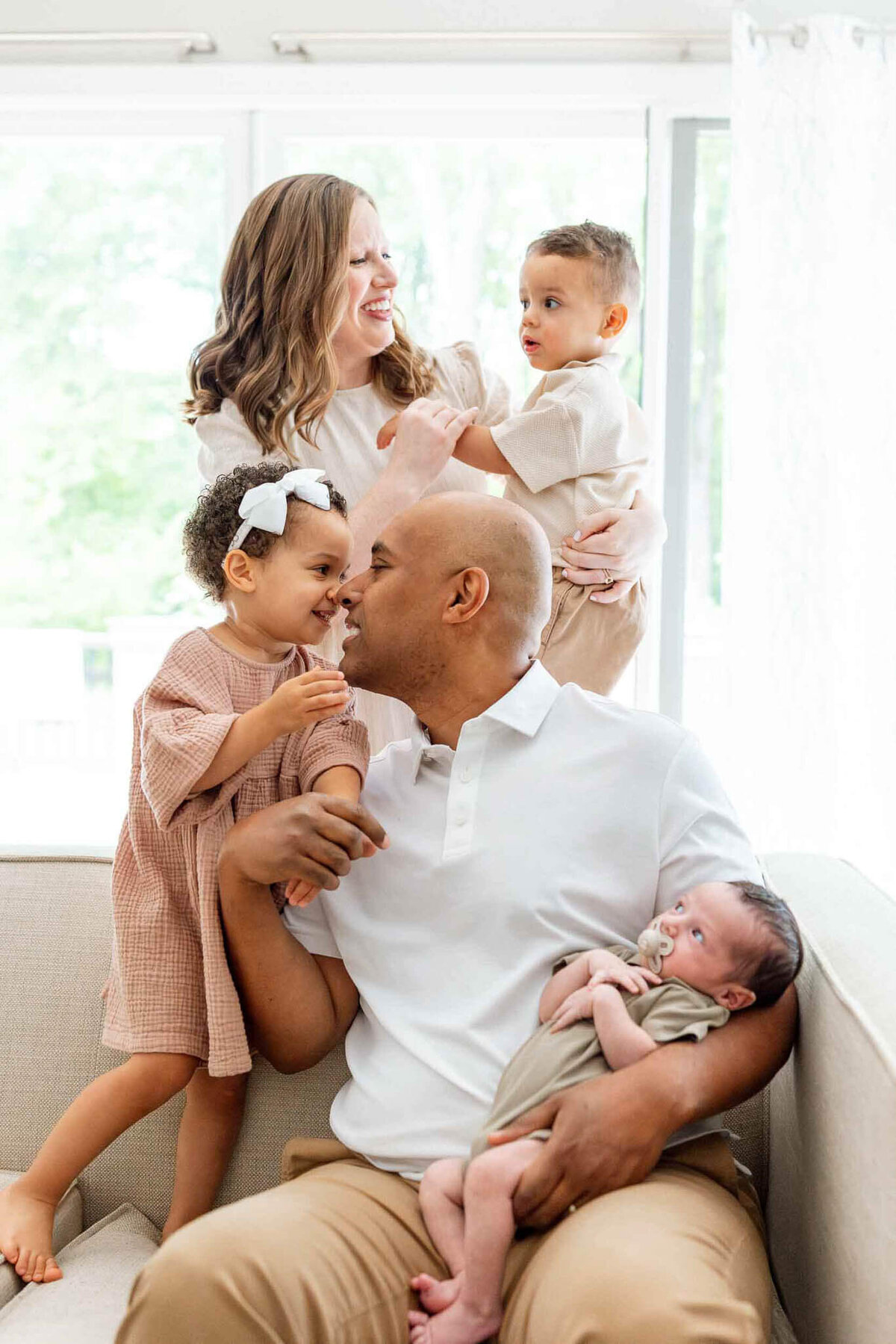 A family of five snuggling in a light and bright living room during Cleveland newborn photography session.