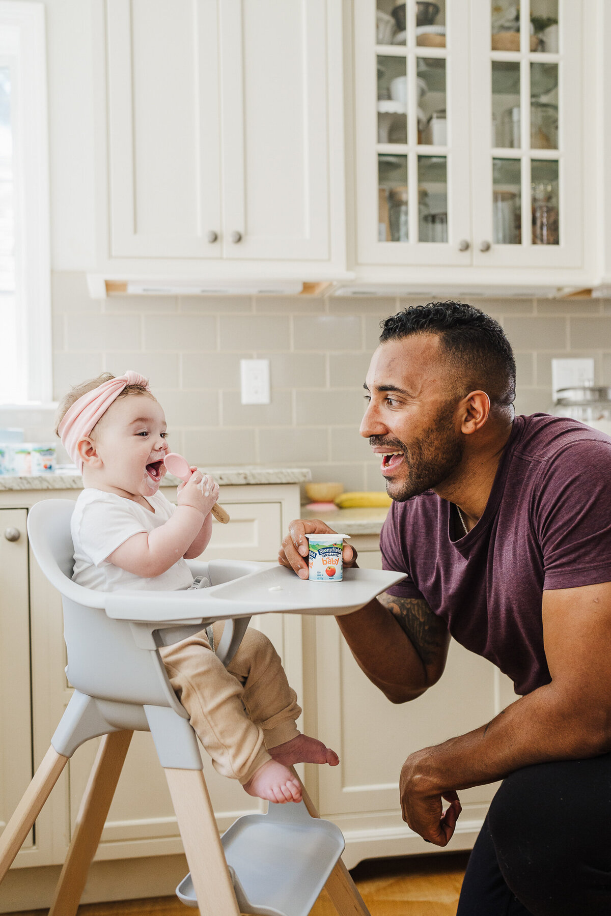 man laughs at baby eating yogurt during stonyfield farm brand photoshoot