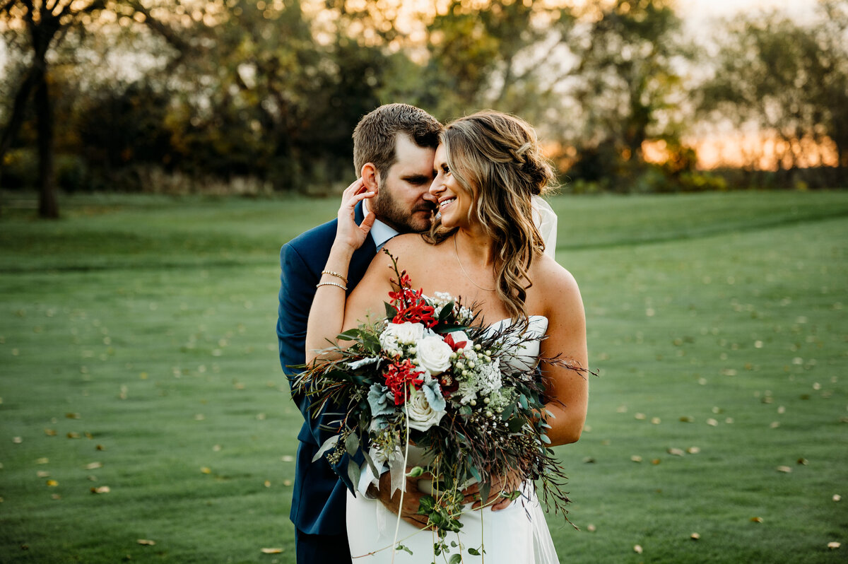 Groom has arms wrapped around bride