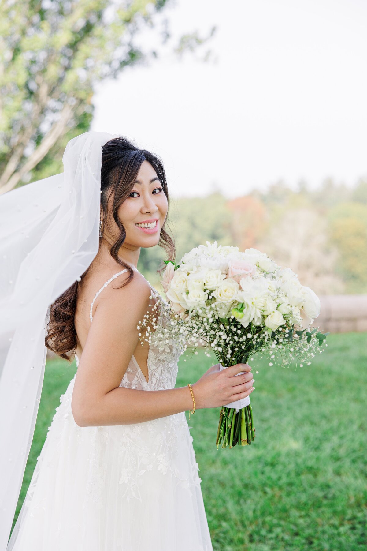 Bride smiling over her shoulder at the camera during her Boston bridal portraits