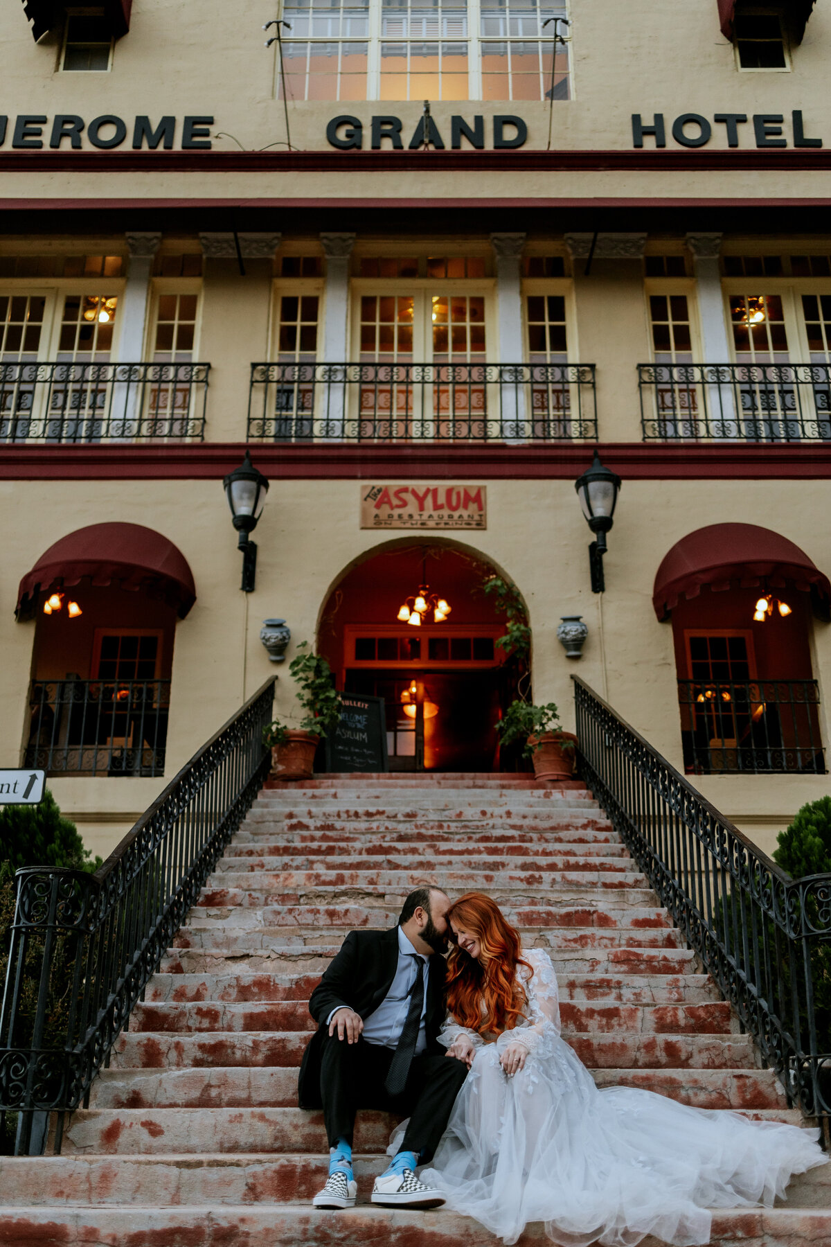 elopement couple laughing on stairs of jerome grand hotel in arizona