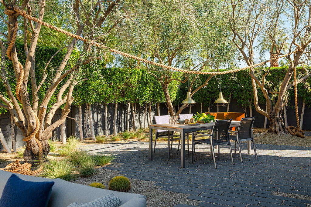 View of backyard dining area with natural stone pavers and olive trees designed by Los Angeles architect.