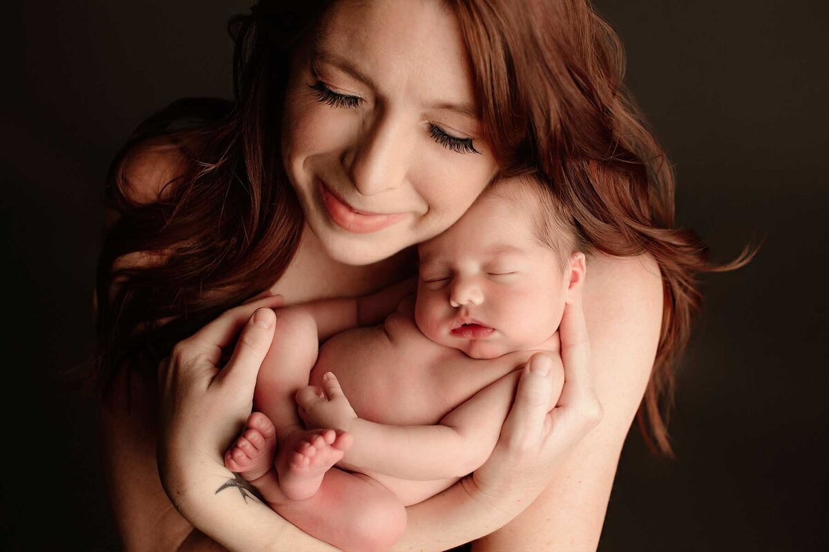 Brightly lit portrait of mother and newborn in her arms