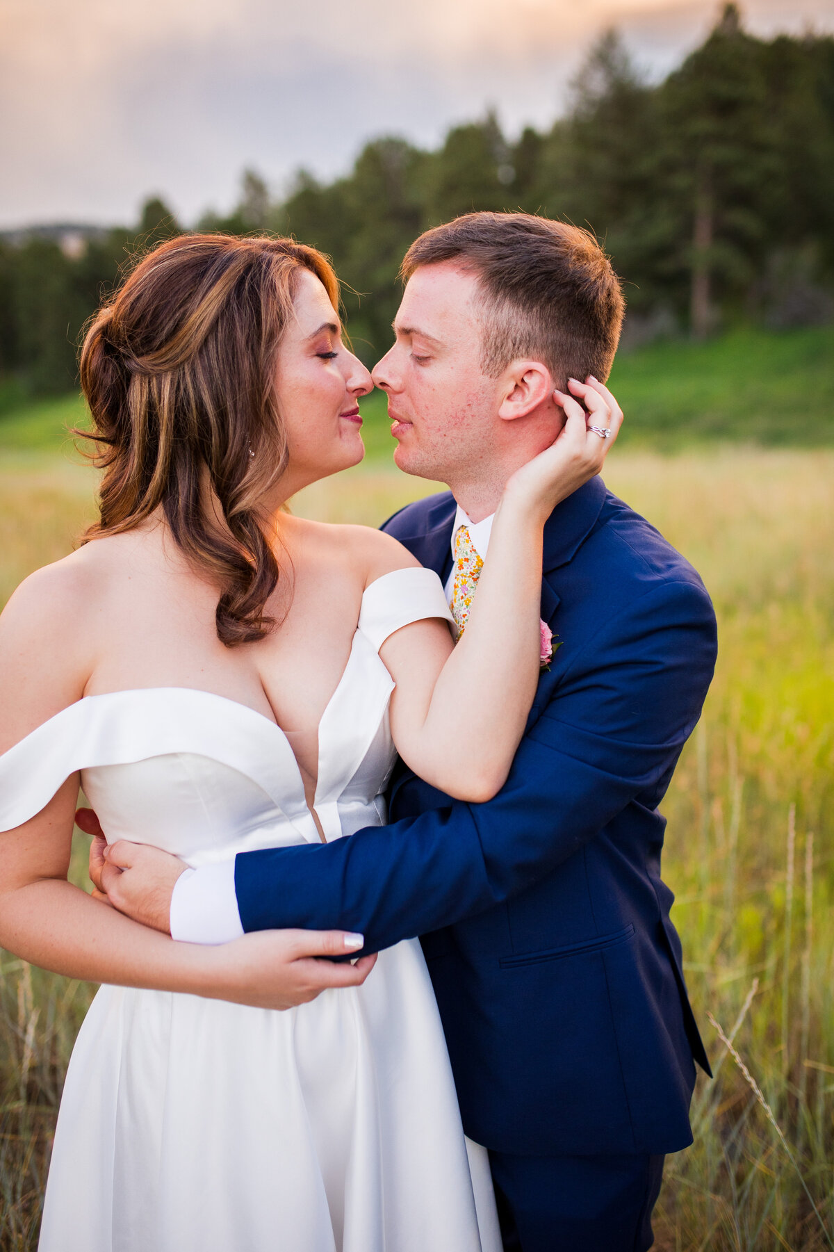 A bride and groom embrace and give eskimo kisses with their noses.