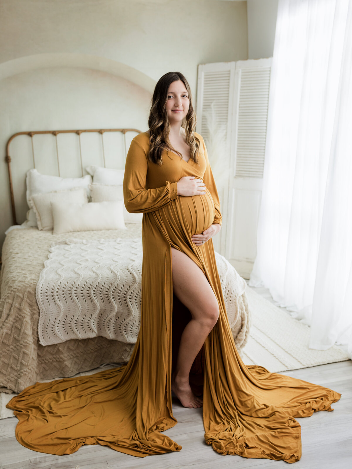 pregnant mother in gold maternity gown holding baby bump for studio maternity photoshoot cleveland maternity photographer