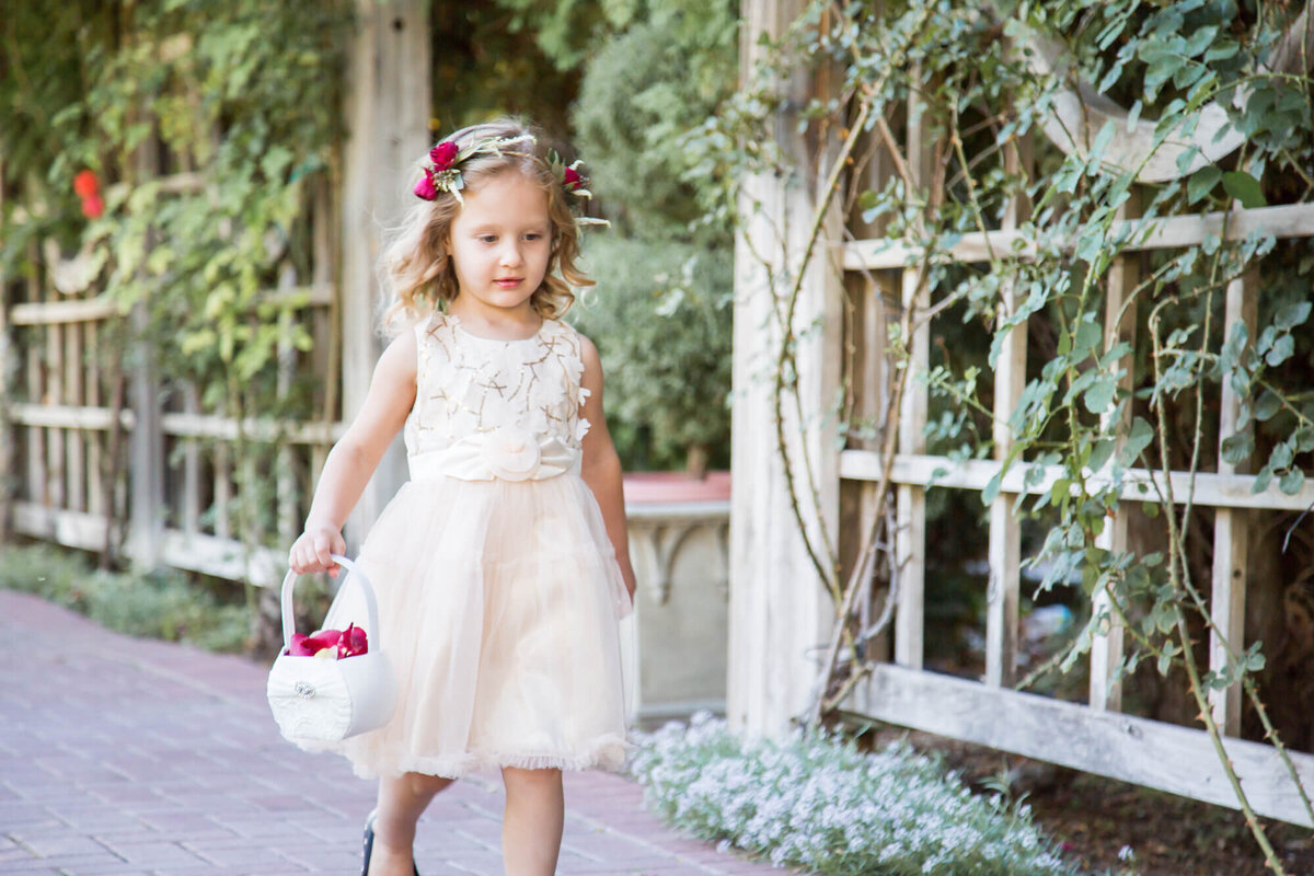 blonde flower girl in cream lace dress walking down the aisle  at lovely garden wedding