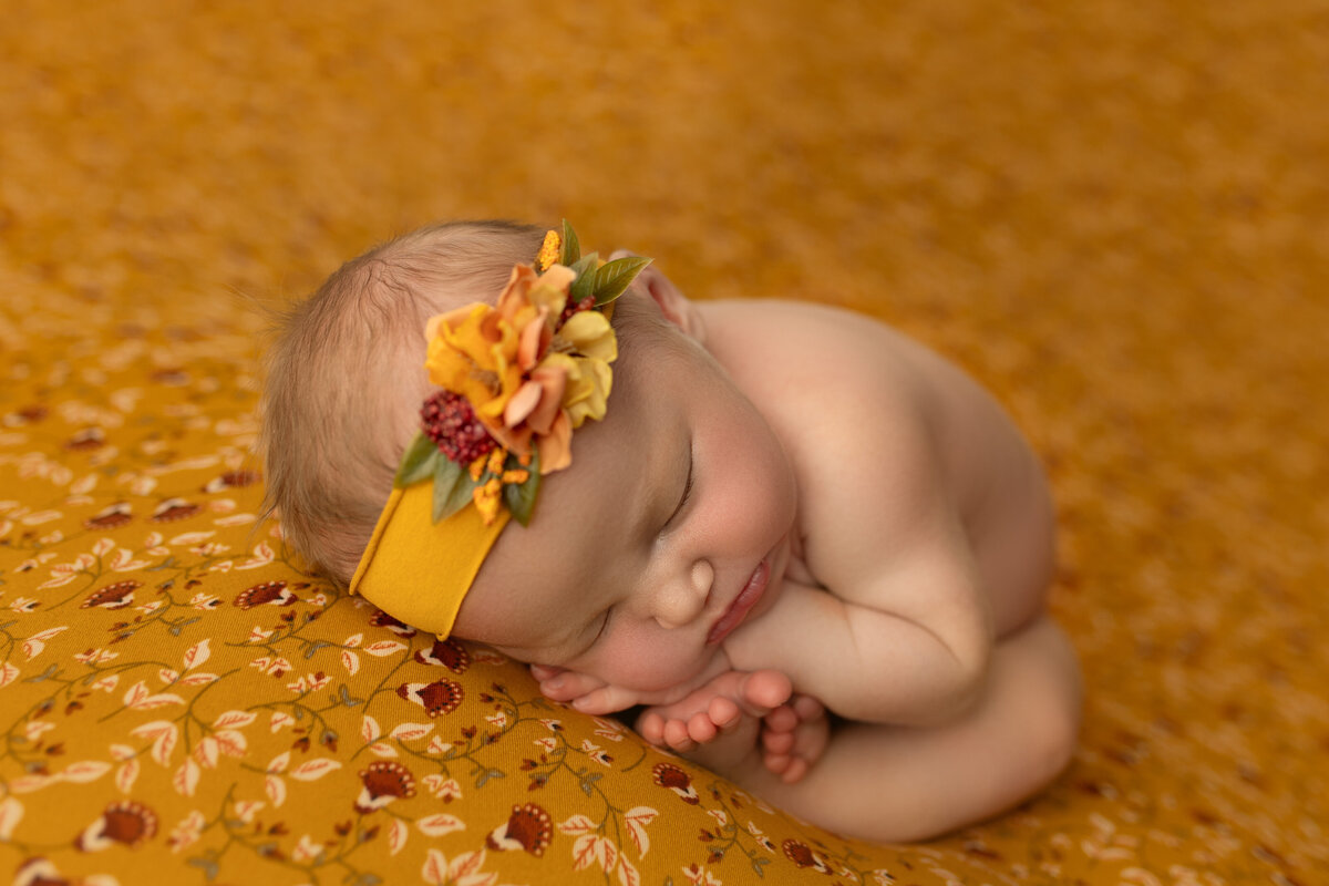 Newborn baby girl in taco pose on yellow florals