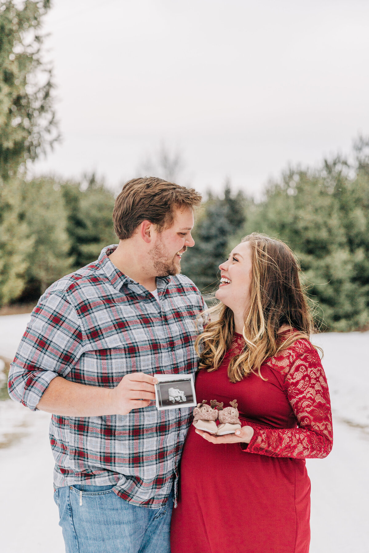 couple hold baby shoes and ultrasound photo looking at each other