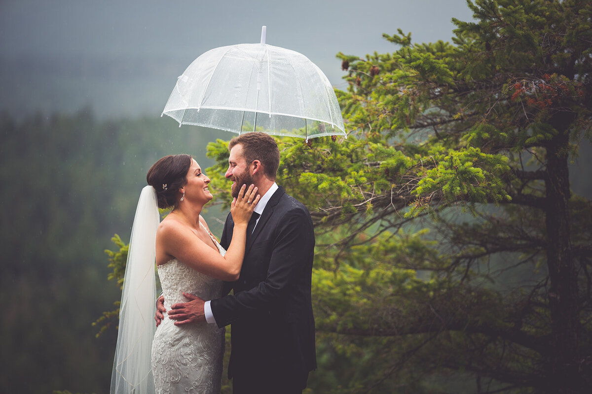A rainy Vancouver Island wedding portrait of a bride and groom with an umbrella.