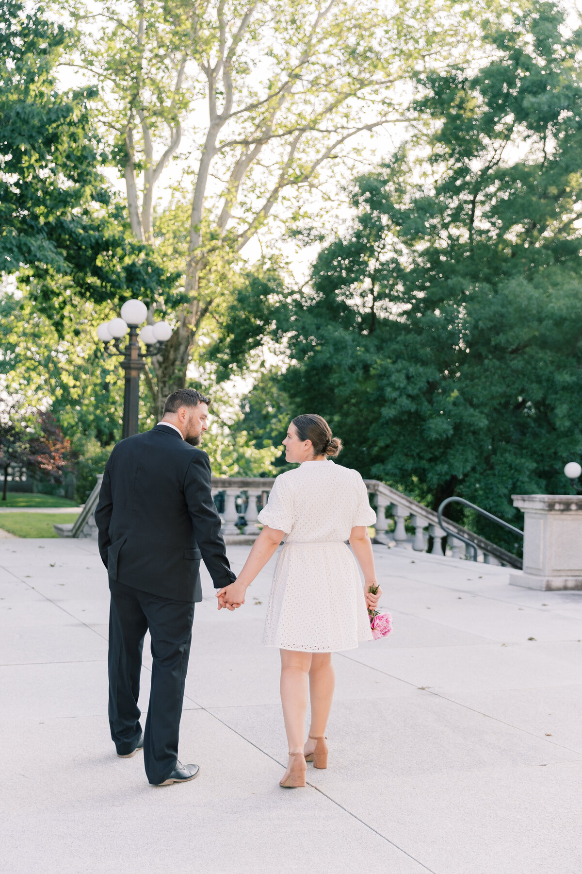Couple holding hands walking away at PA State Capitol during engagement session
