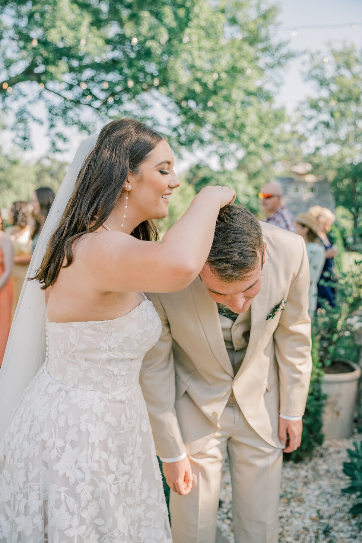 Bride removes florals from groom's hair after their wedding ceremony at Three Oaks Manor