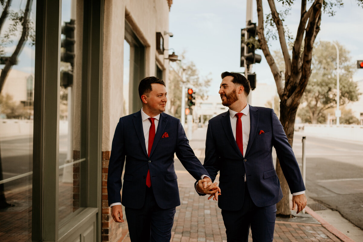 same sex couple walking downtown in Albuquerque in their wedding suits