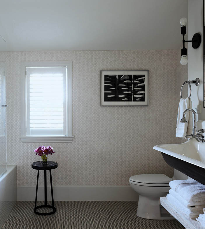 Discover the kids bath in a historic Hingham home, featuring a penny tile floor and matching wall, a trough sink, and a simple yet functional design perfect for sharing.