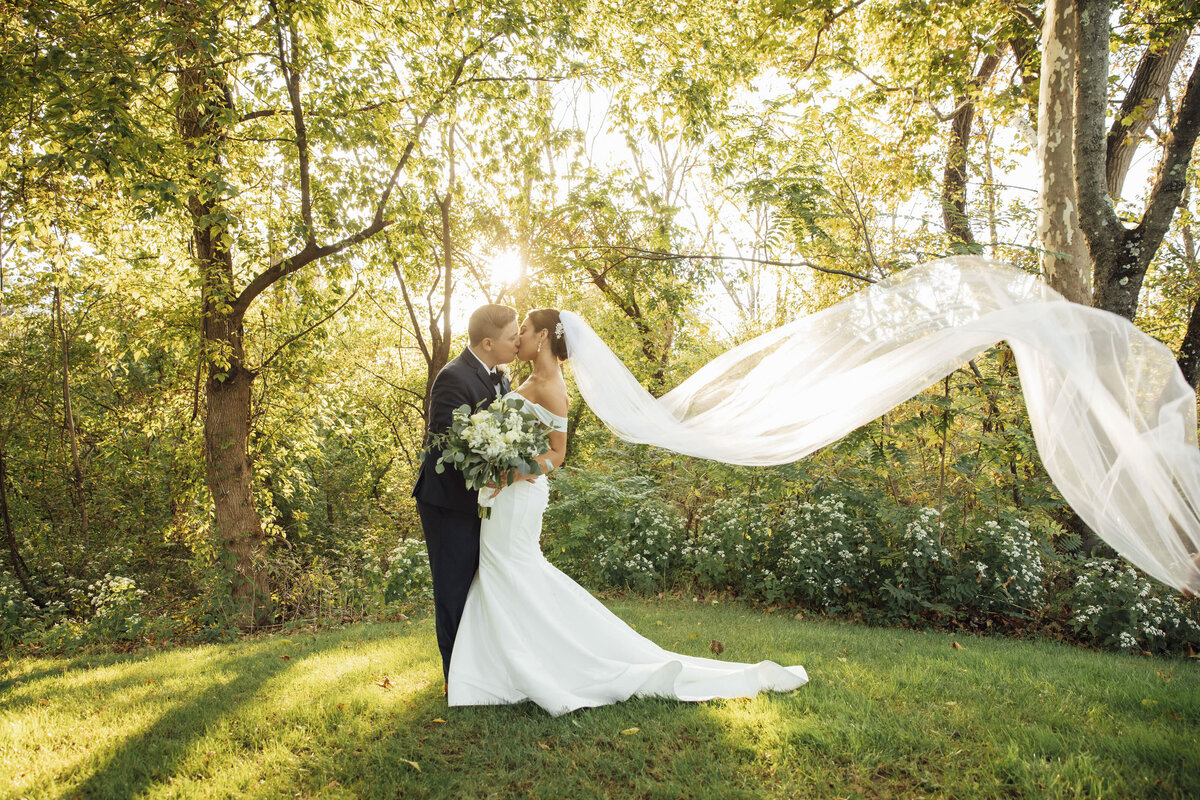 Hamilton Manor | Bride and groom kissing with flowing veil at sunset during summer wedding | Hamilton Township, New Jersey