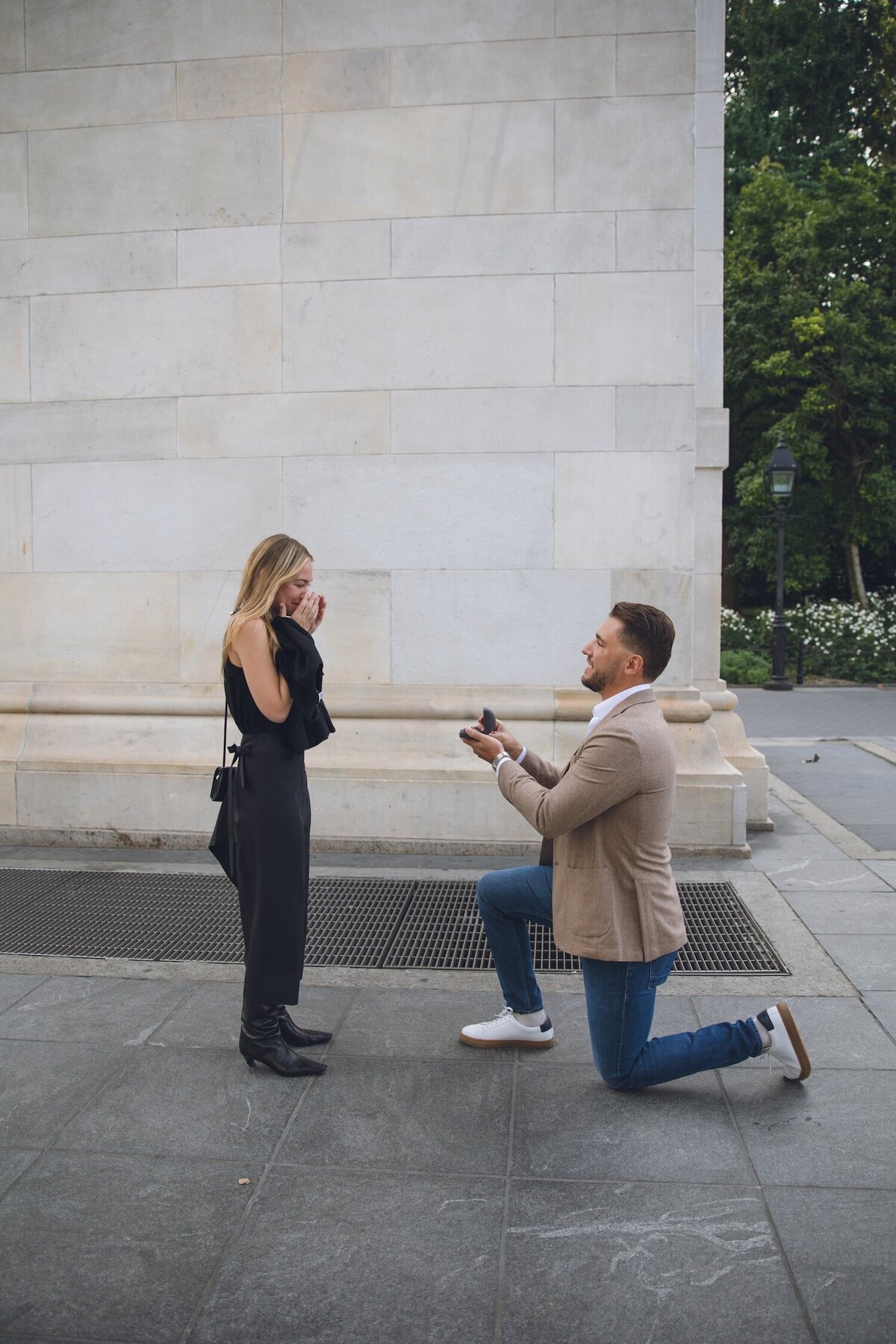 Groom kneeling and proposing at Washington Square Park.