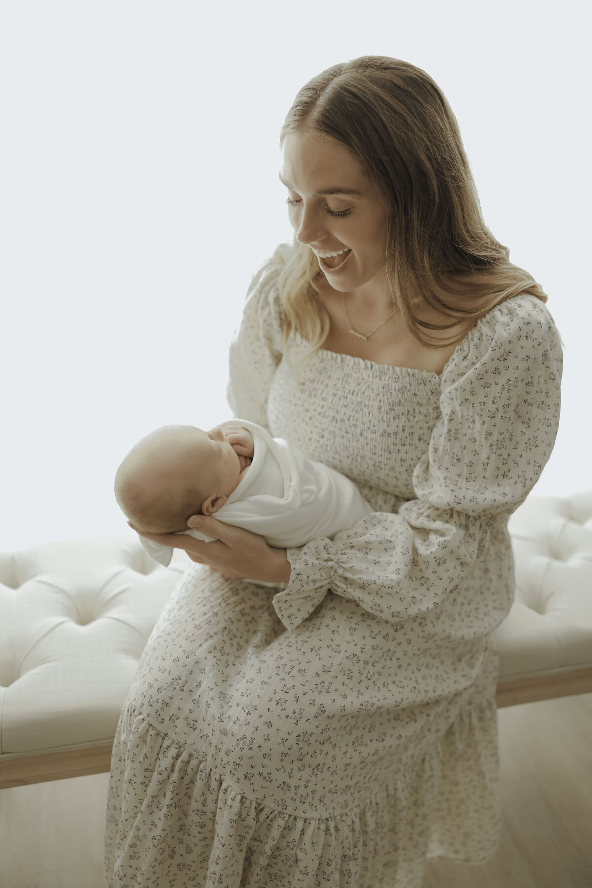 mother smiling while holding swaddled newborn