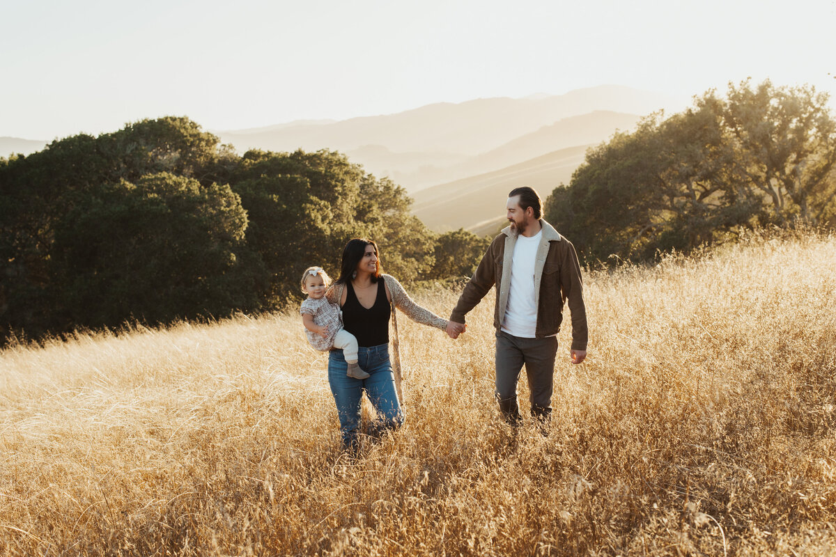 A family walks amongst the wam sun lit grass in petaluma, california