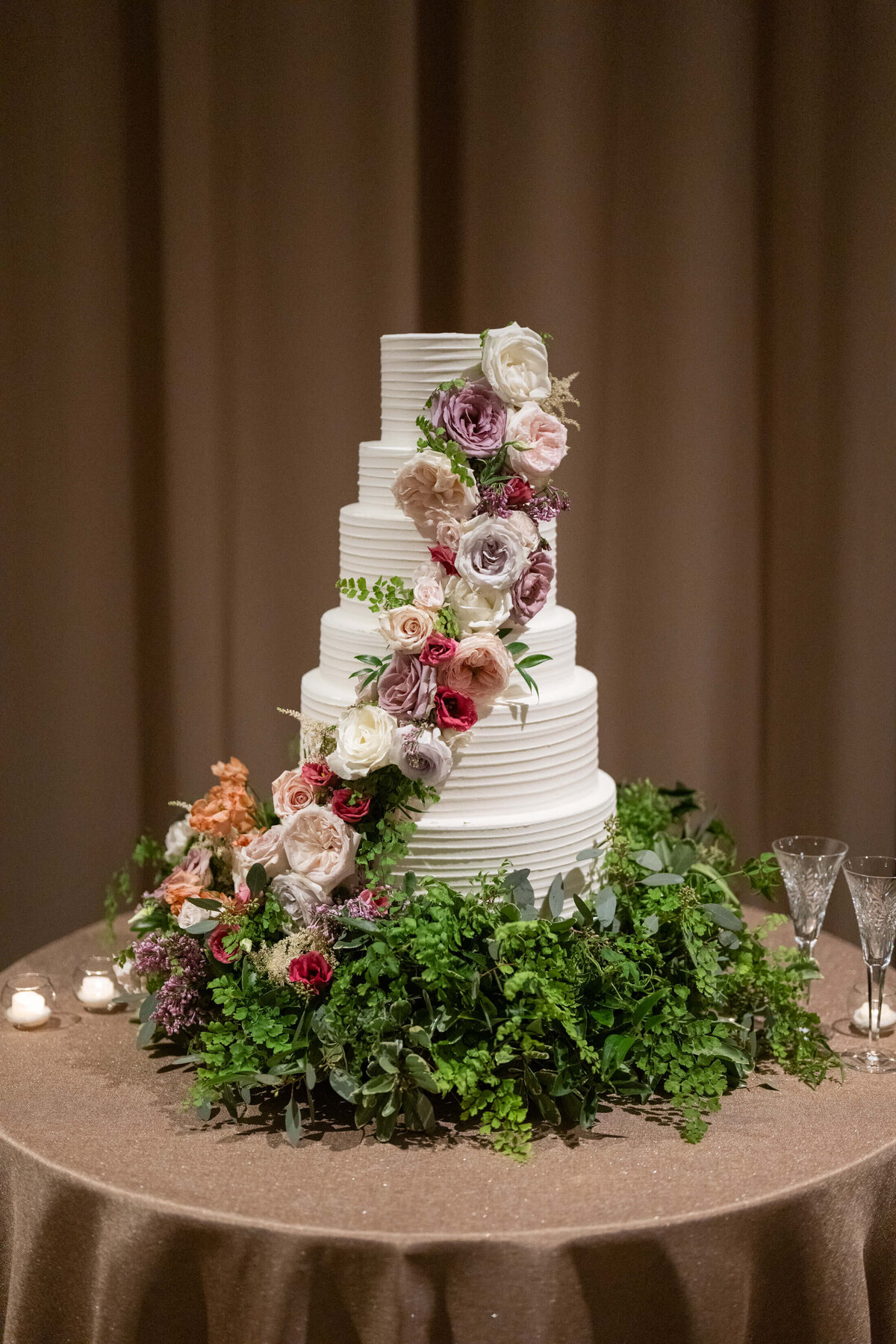 Six tier white wedding cake covered in fresh flowers