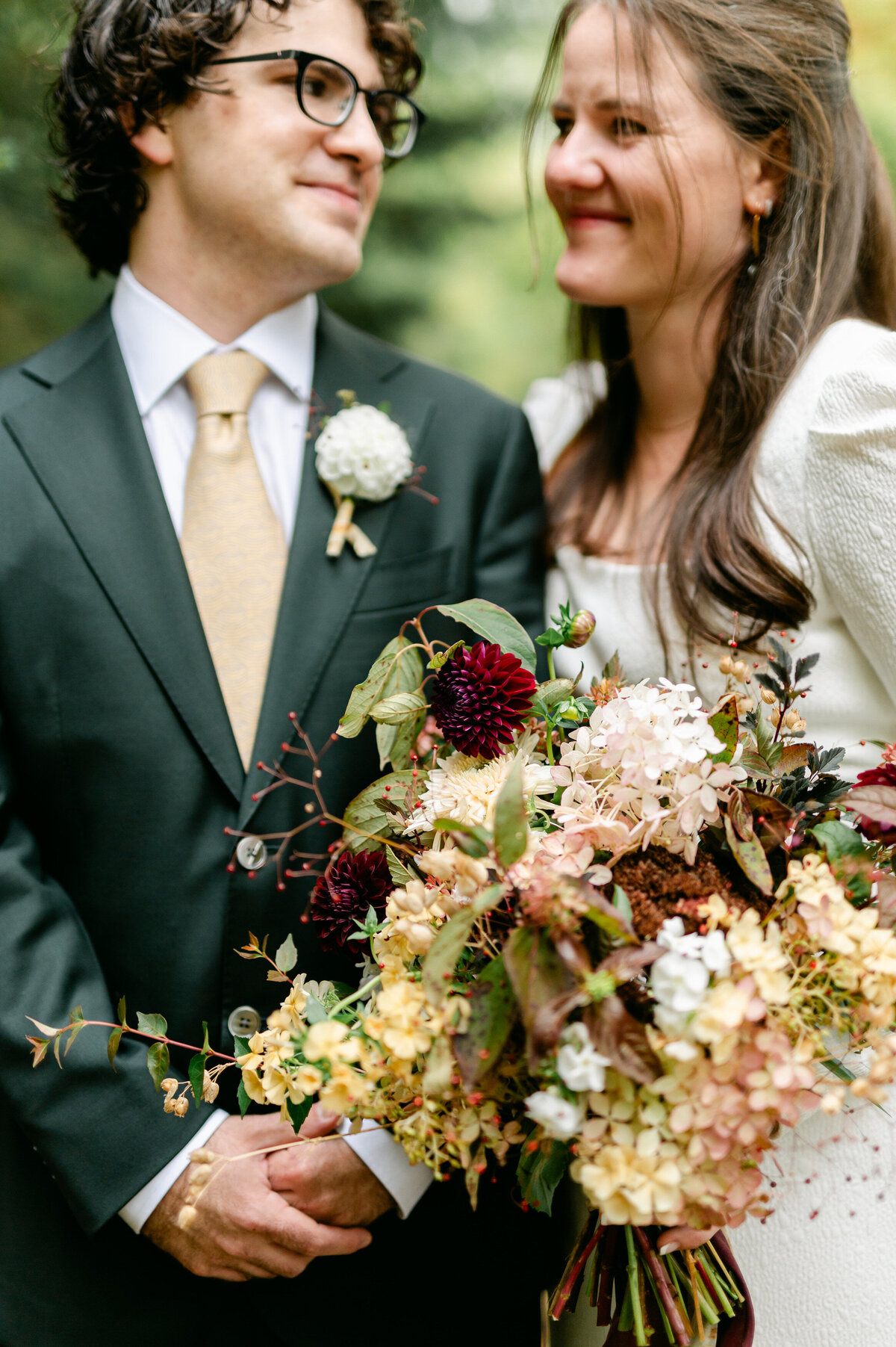 Bride and groom smiling at each other with wedding bouquet close up