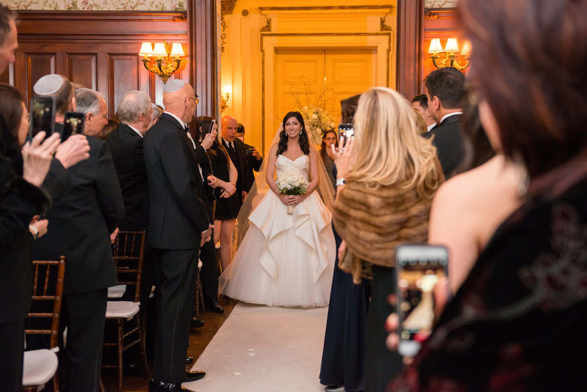 Bride walking down the aisle during the wedding ceremony at The Bourne Mansion