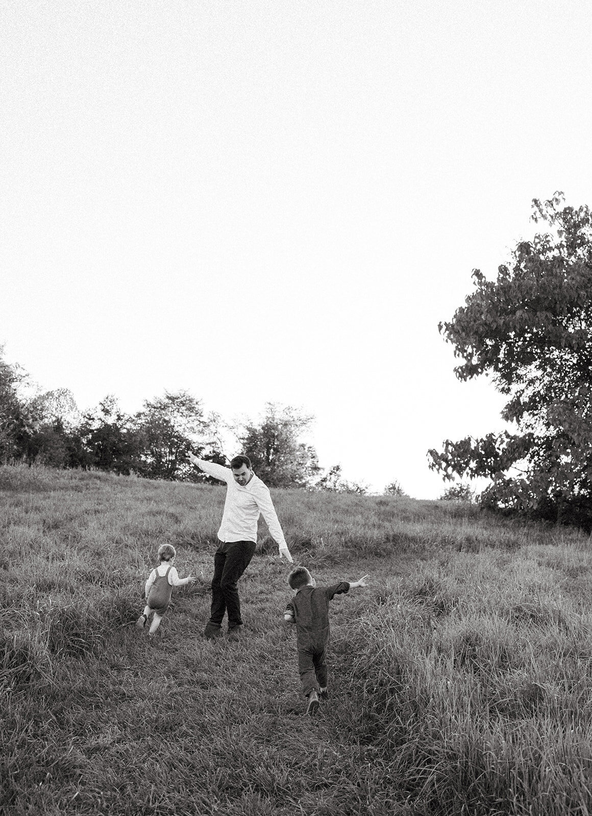 Father running around playing airplane with his sons