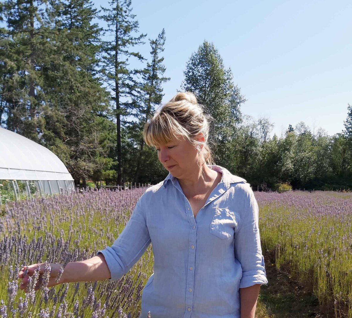 Susan Wyatt standing in a lush garden, smiling, showcasing her expertise in plant propagation and landscape design.