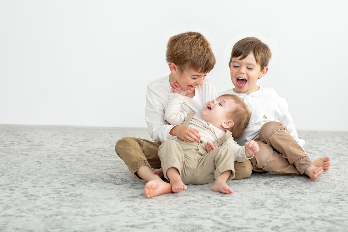 Three young boys smiling and playing together during their family photo session