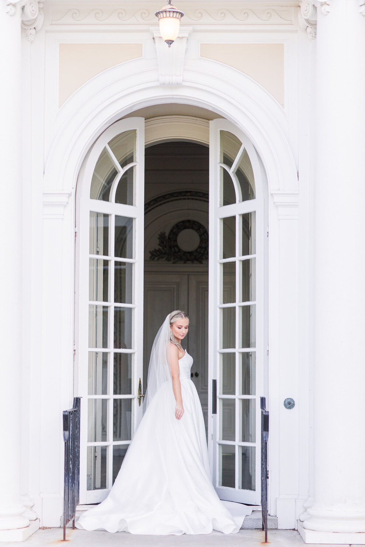 Bride adjusting her dress in between doors at Tupper Manor