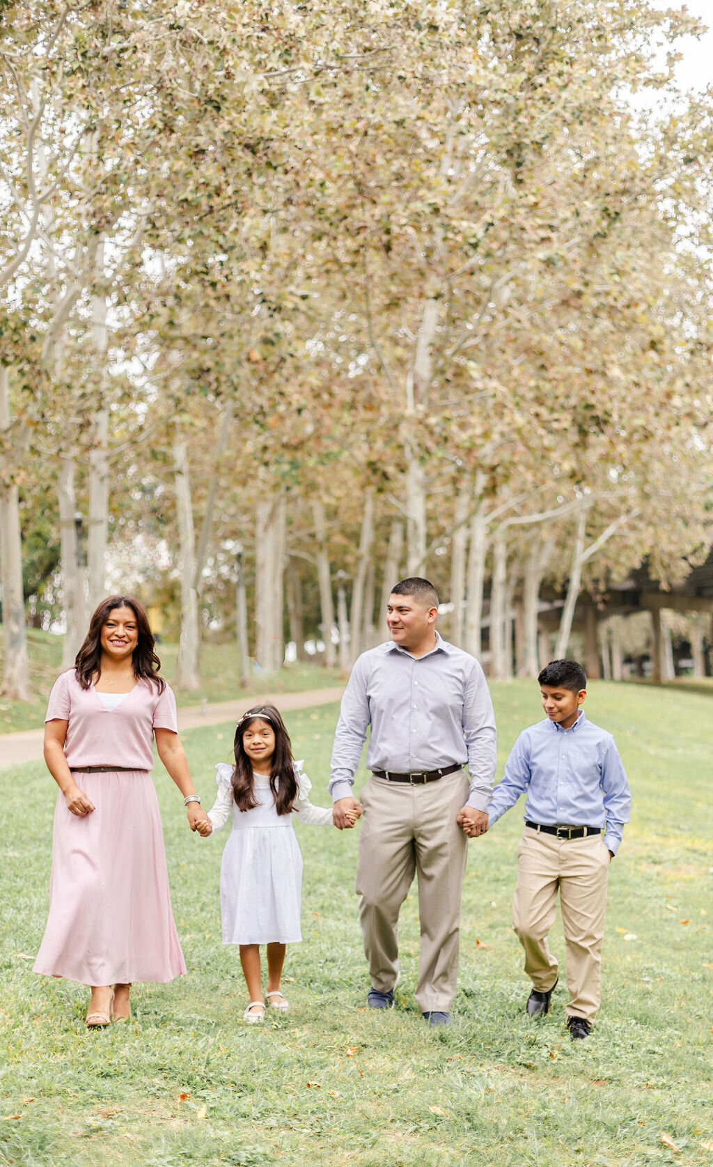 Family portrait under the Sabine Bridge in Houston with a family of four smiling and holding hands