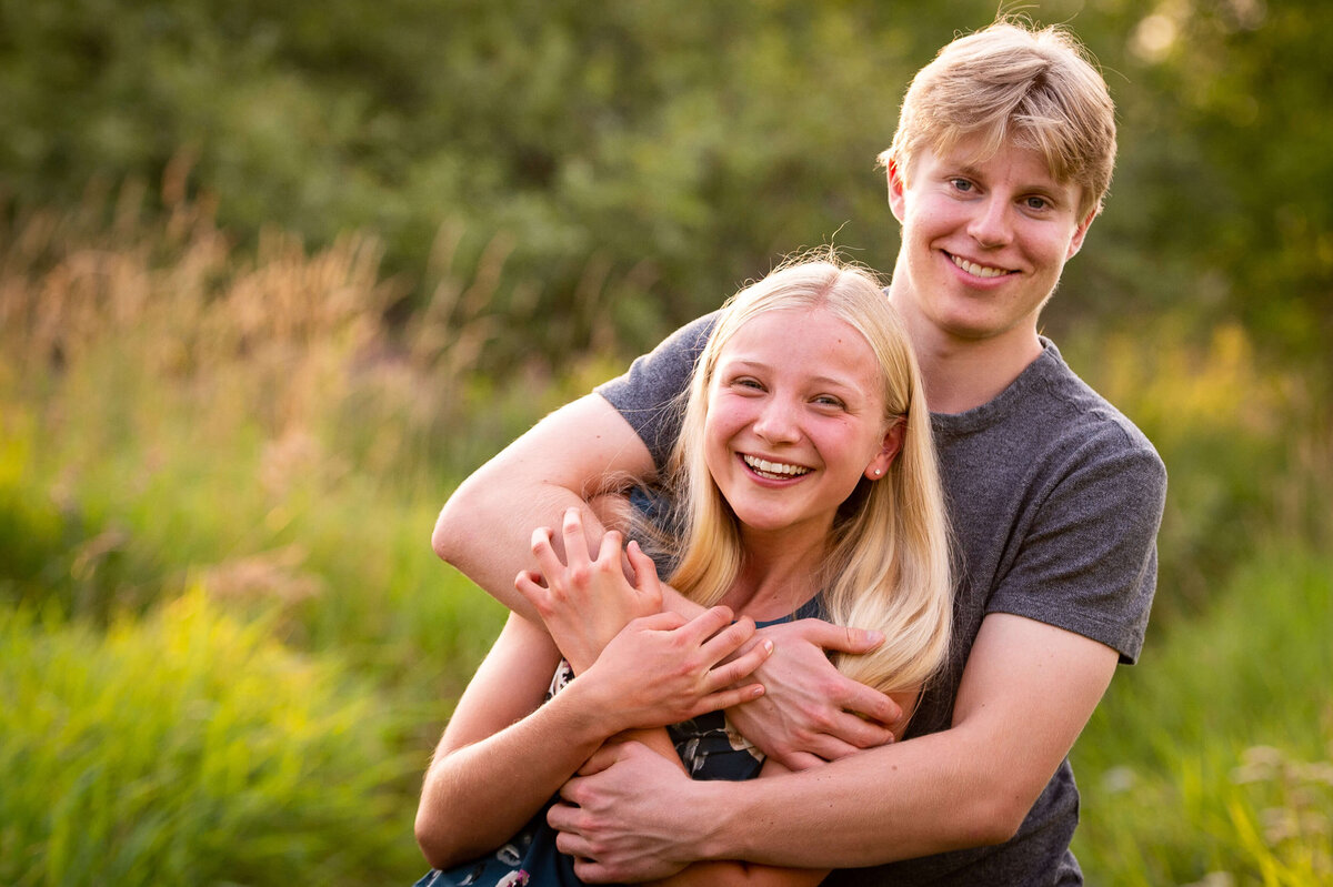 a teenage brother hugs his teen sister during their family session taken by Ottawa Family Photographer JEMMAN Photography