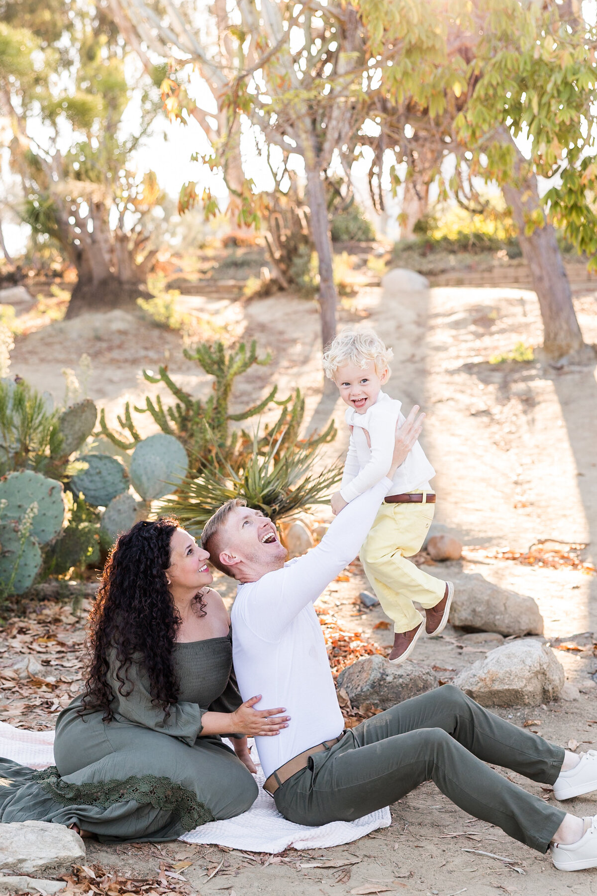 parents sitting holding up son in Cactus garden Balboa Park San Diego