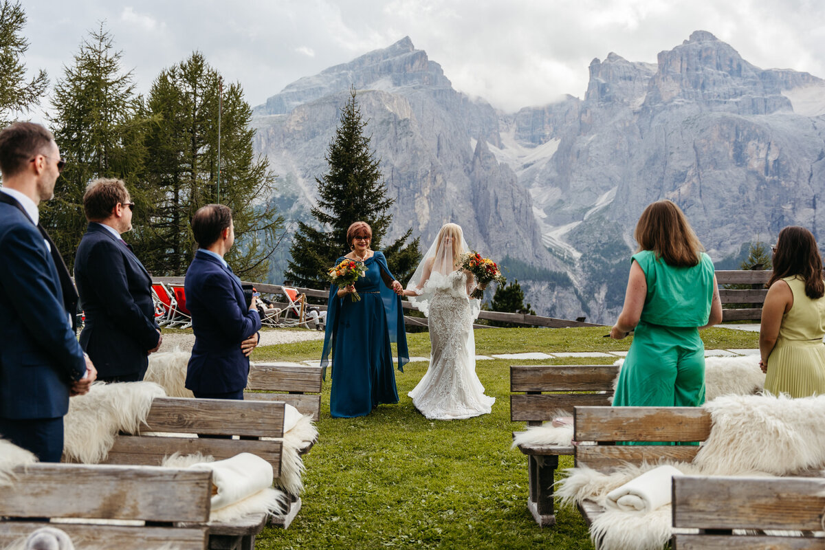 Outdoor Dolomites wedding ceremony with floral arch and mountain views