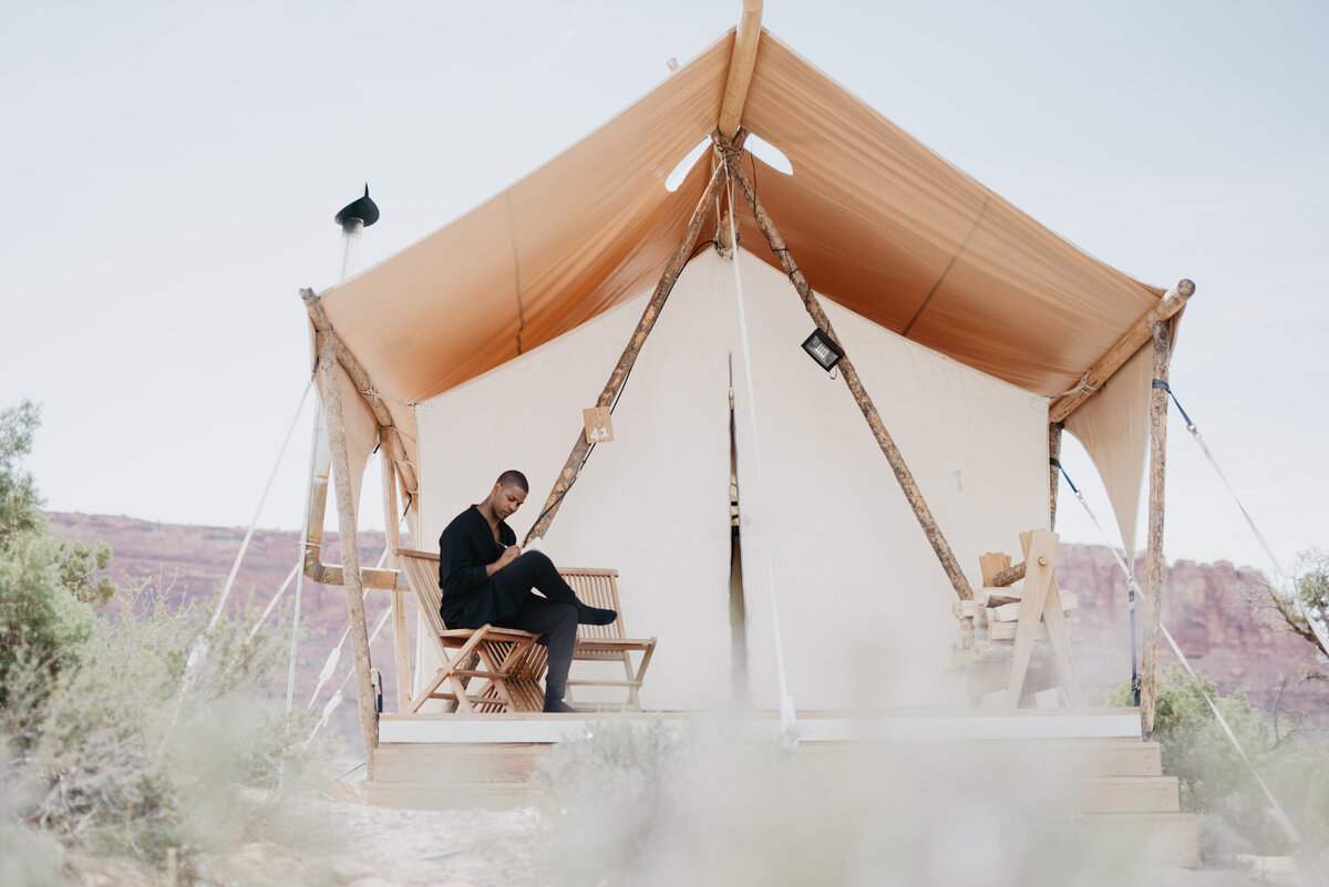 Utah Elopement Photographer captures man sitting on bench outside of Moab teepee