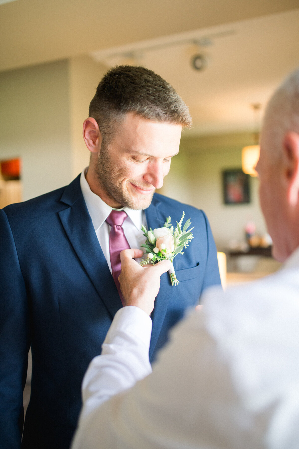 Boutineer being put on by father of groom captured by Niagara wedding photographer