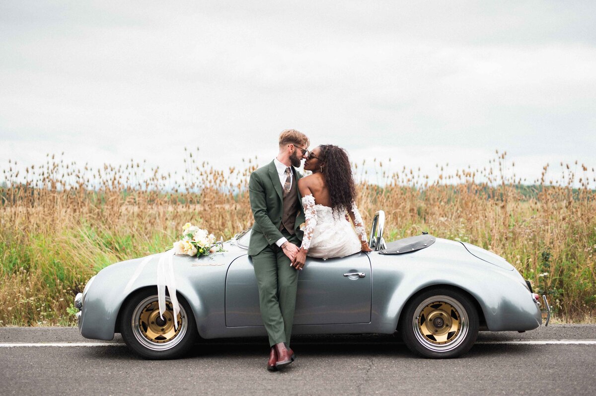 biracial couple in wedding attire in their vintage porsche convertible at maysara winery