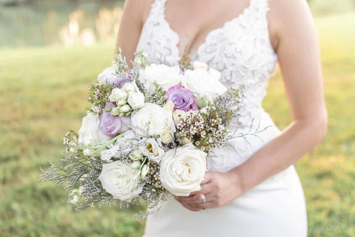 Bride holding a bouquet with white and purple roses