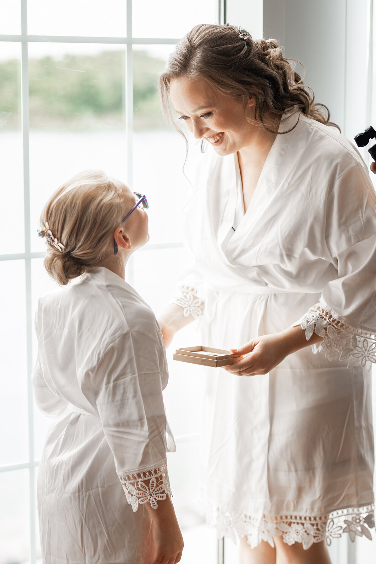 bride and little girl in robes sharing gift