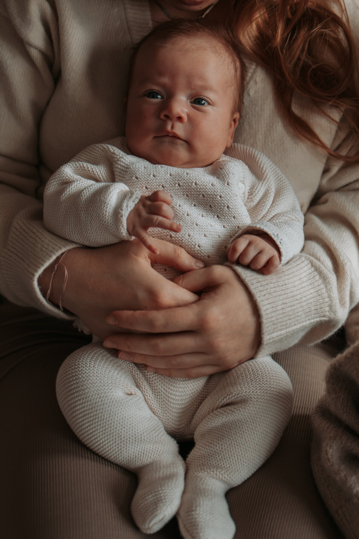 Een vrouw houdt een baby in haar armen, met een liefdevolle en zorgzame uitstraling.
