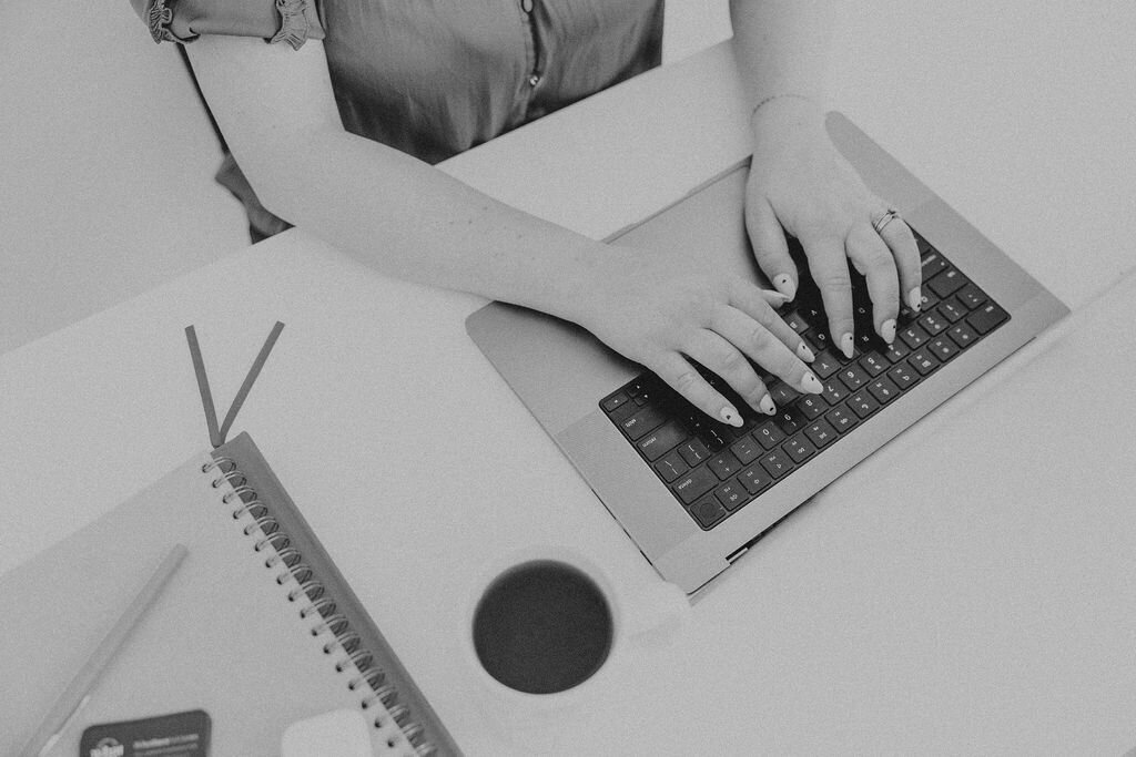White desk with white flowers, coffee, and computer keyboard