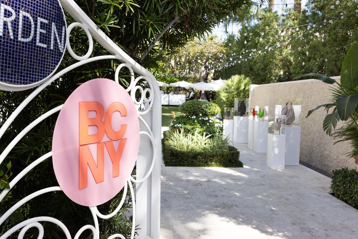 BCNY sign mounted on garden gate with pathway and greenery beyond at the event.