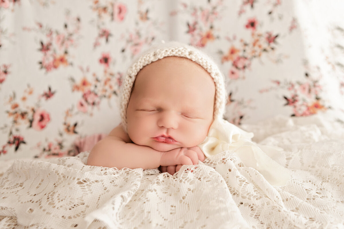 newborn in bonnet on lace and floral background