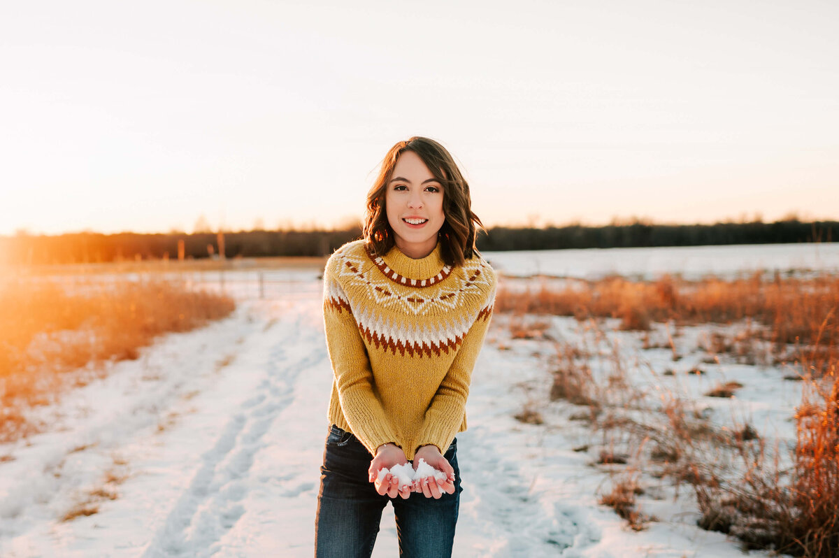 Branson senior photographer captures senior girl holding snow at sunset