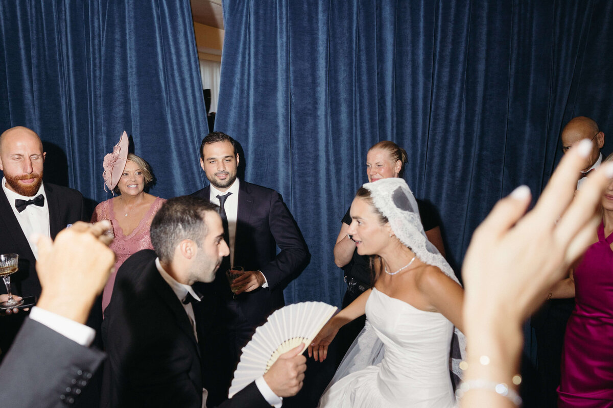 Bride smiling while dancing with guests during wedding party

