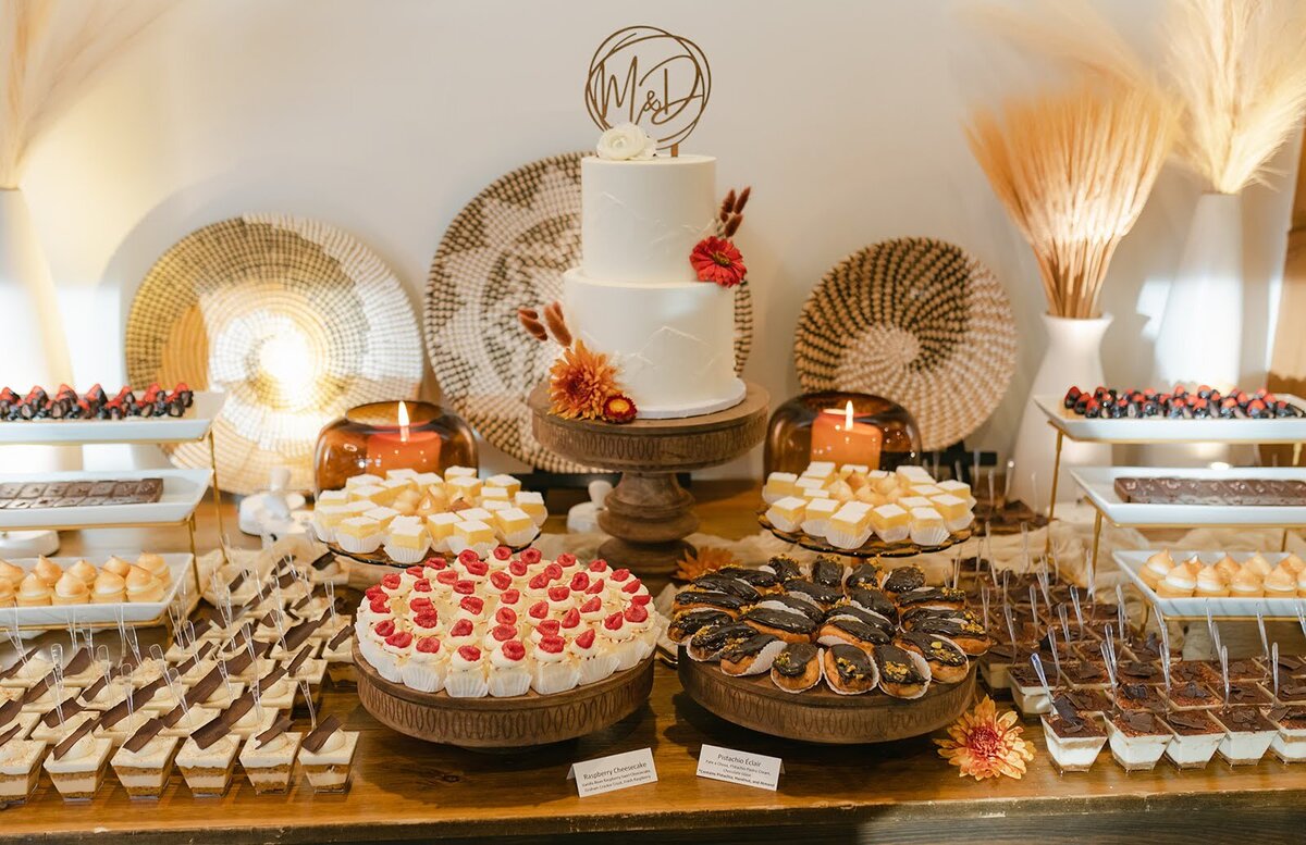 Wedding dessert setup at North Star Gatherings with warm fall colors, wooden cake stands, and pampas grass arrangements.