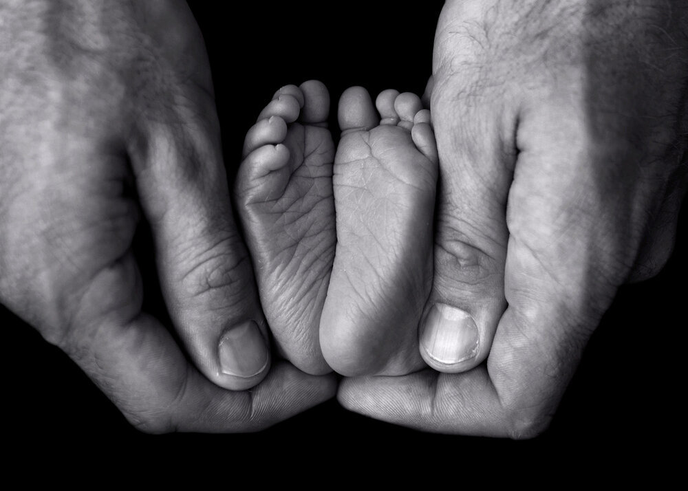 NEWBORN_BABYFEETINHANDSBLACKWHITE