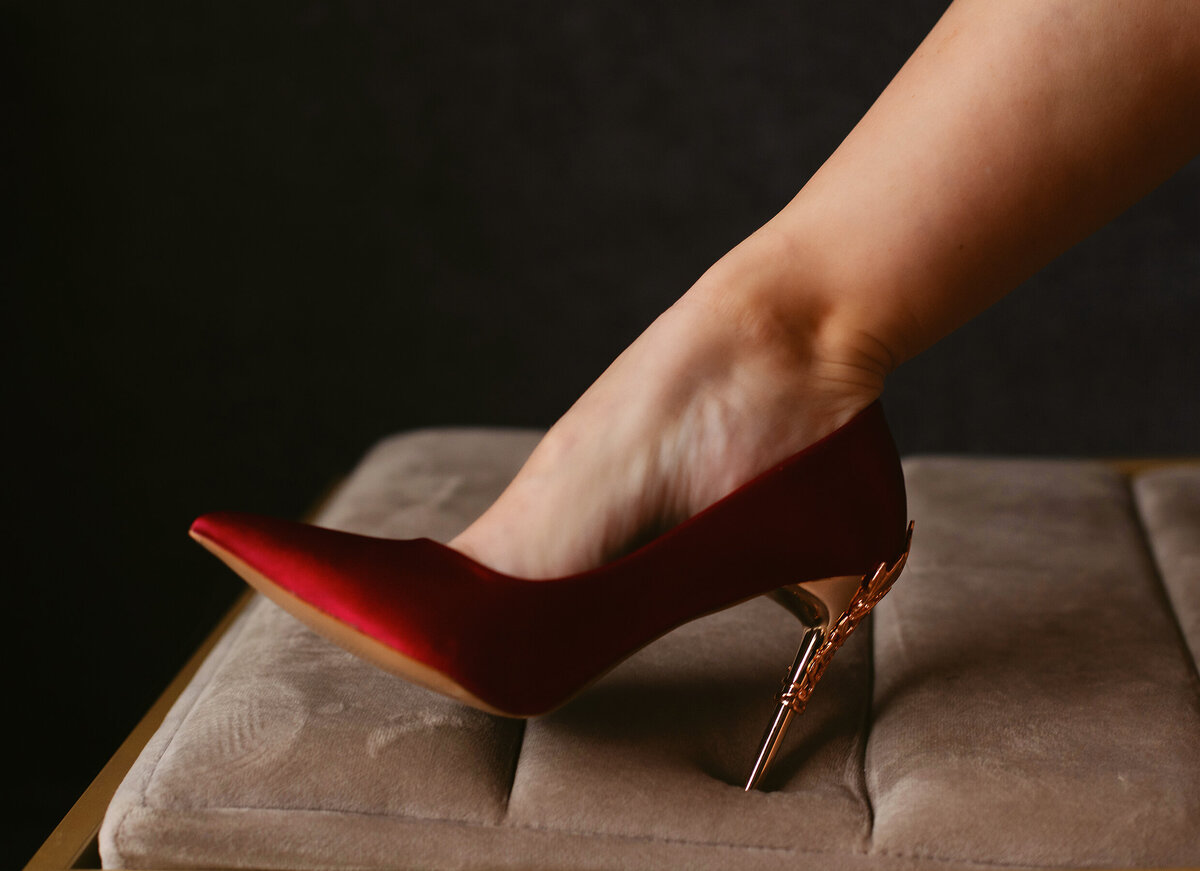 A sexy red shoe is worn during a boudoir photoshoot.