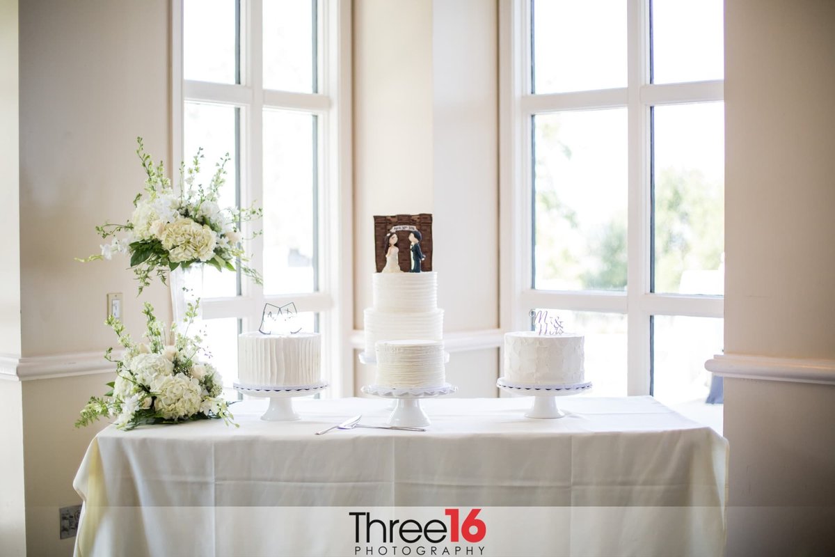 Beautiful white 2-tiered wedding cake with 3 smaller side cakes